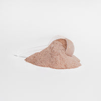 A scoop of chocolate-flavored collagen powder being added to a drink.