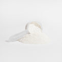 A scoop of unflavored collagen powder being added to a glass of water, highlighting its mixability.