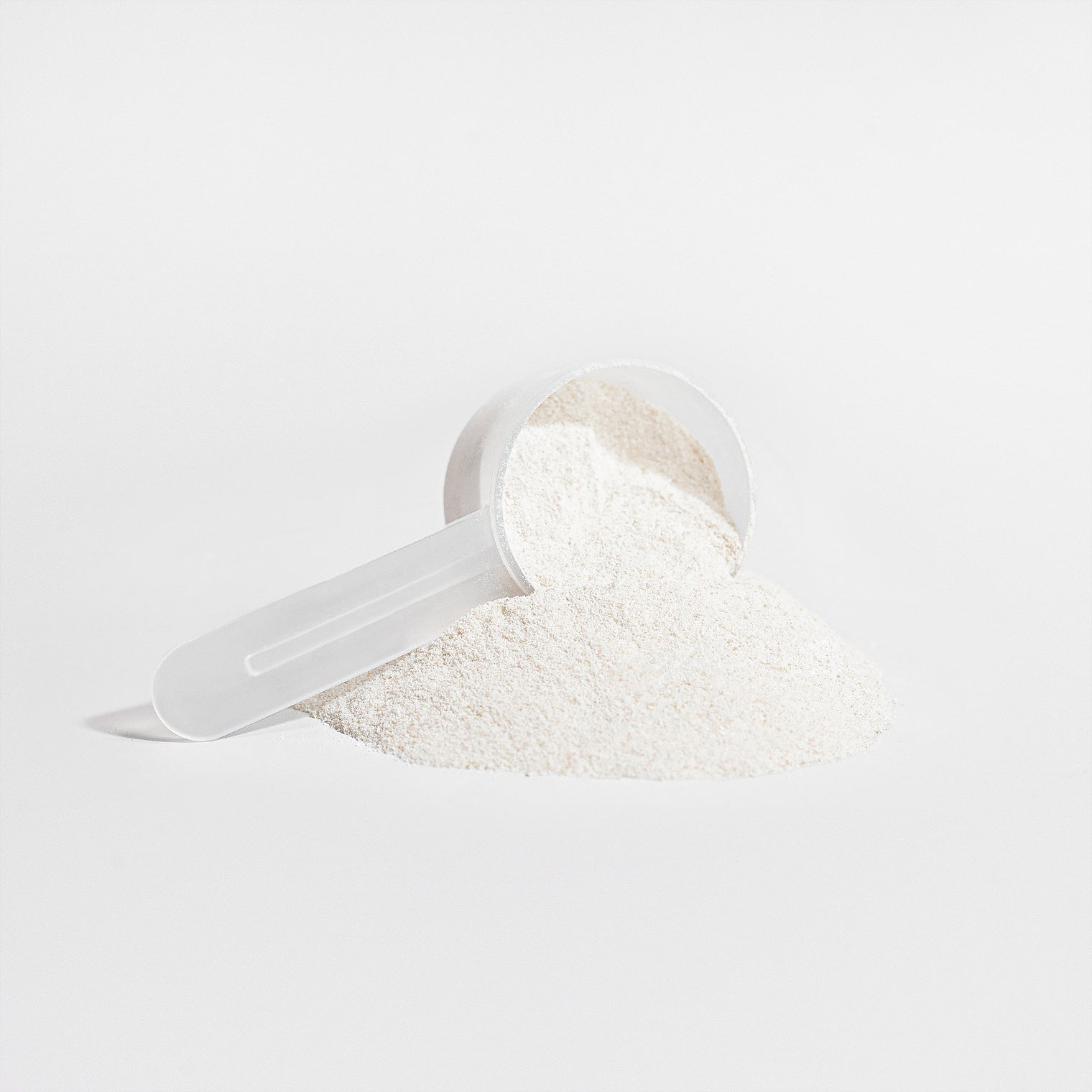 A scoop of unflavored collagen powder being added to a glass of water, highlighting its mixability.